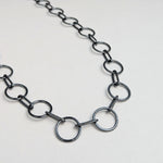 A close-up image of a sterling silver circle chain necklace with a hand-fabricated S-clasp.