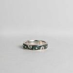 Silver ring with embedded green sapphires on a gray background